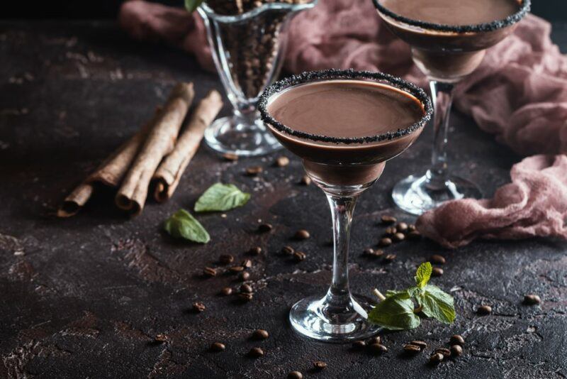 Two glasses of chocolate martini cocktail next to cinnamon sticks