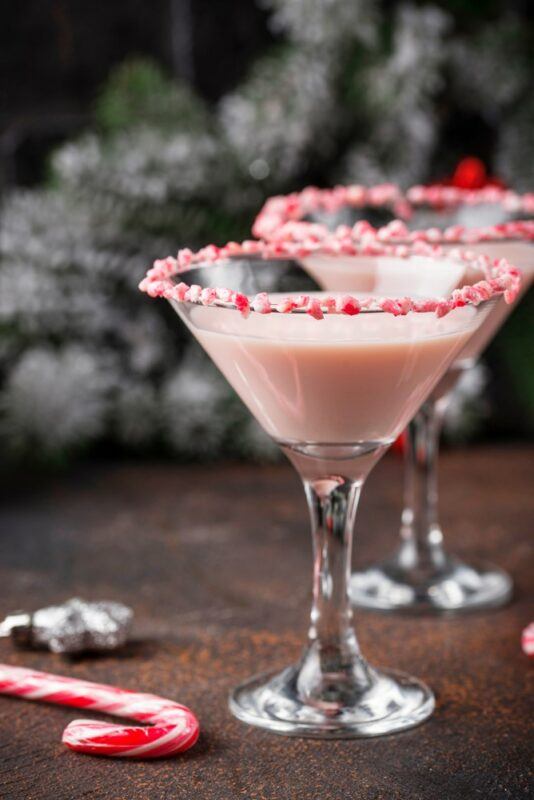 Two glasses containing a chocolate peppermint cocktail that uses candy cane pieces on the rim