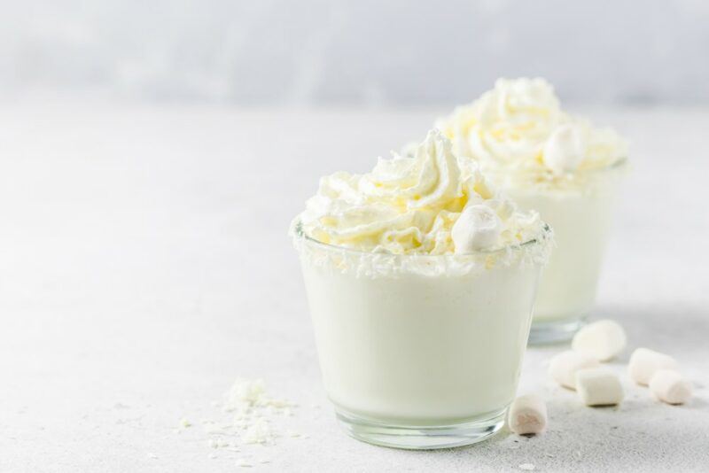 Two glasses of a cottontail margarita with whipped cream on top on a white table