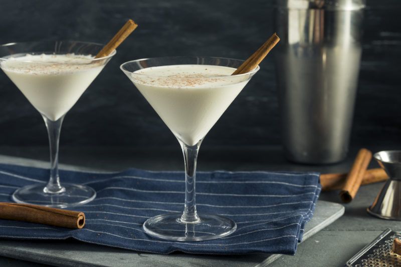 Two eggnog martinis on a tray with cinnamon sticks as a garnish