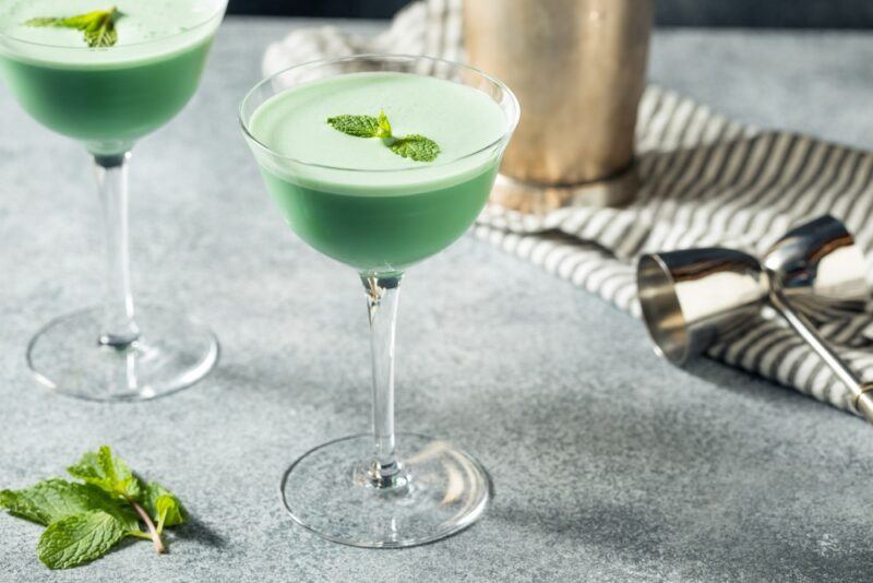 Two coupe glasses containing a green grasshopper cocktail