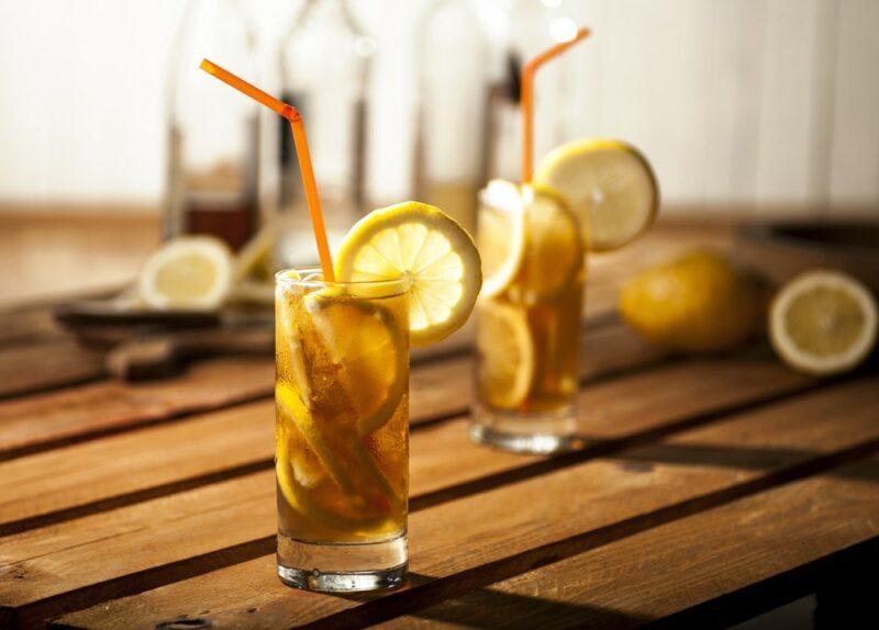 Two glasses that contain honey whiskey iced tea on a wooden table