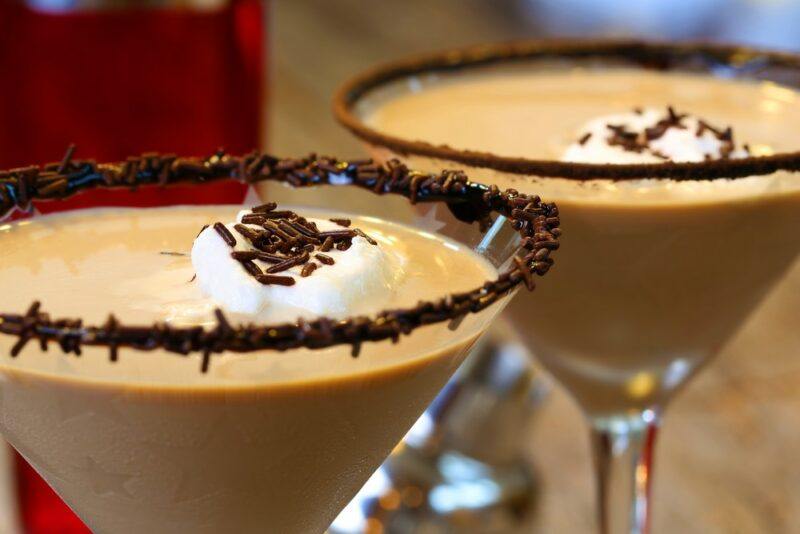 Two martini glasses that contain a creamy peanut butter whiskey cocktail, with a chocolate garnish and some marshmallows