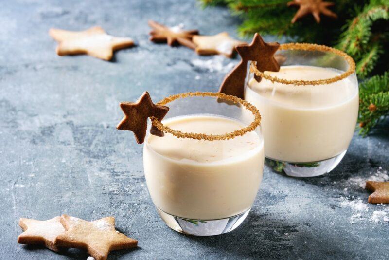 Two glasses containing a sugar cookie cocktail garnished with a star, with a cinnamon sugar rim, with more stars on the table