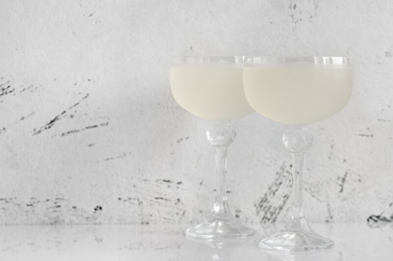 Two glasses containing a white lady cocktail against a light background