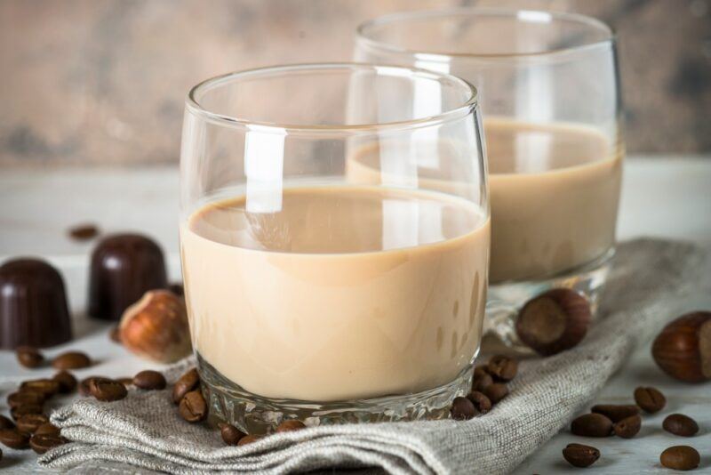 Two glasses containing an Irish daddy cocktail, next to hazelnuts and chocolate