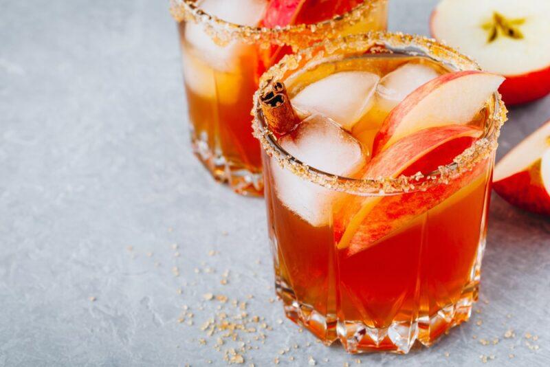 Two mugs of an apple cider margarita that has been rimmed with sugar