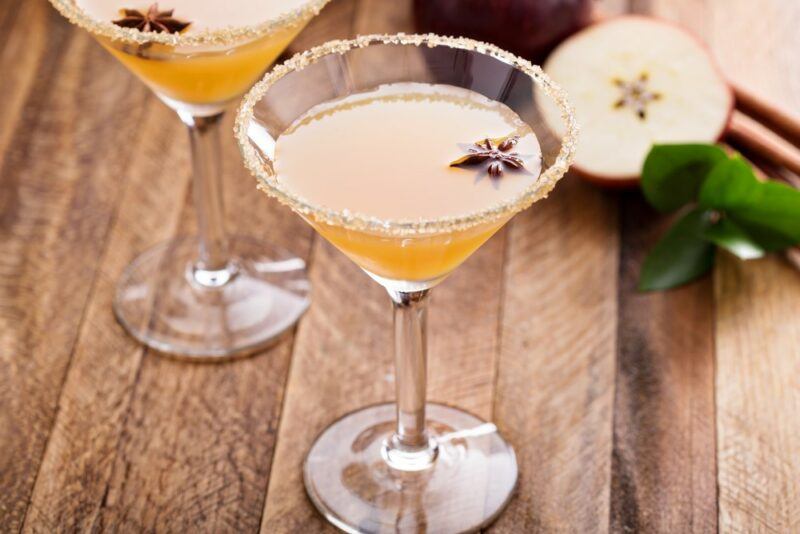 Two glasses of an apple pie martini, which have an apple slice and a single star anise as a garnish