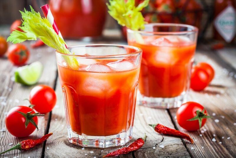 Two glasses with ice and a bloody Mary cocktail, each garnished with a sprig of celery