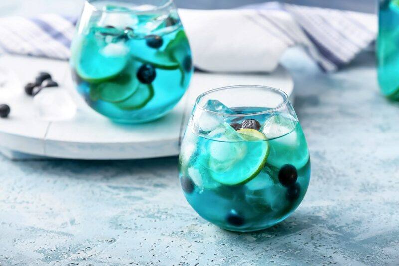 Two glasses of a blue party punch called blue kool-aid jungle juice