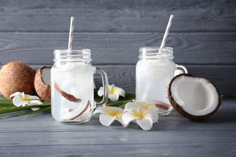 Two mason jars with coconut water and coconuts