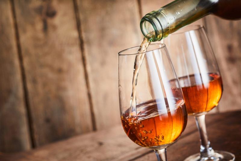 Two glasses of fortified wine being poured from a bottle