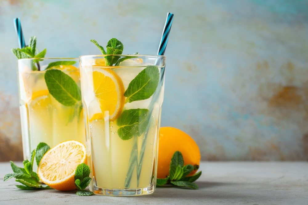 Two glasses of lemonade with fresh fruit and straws