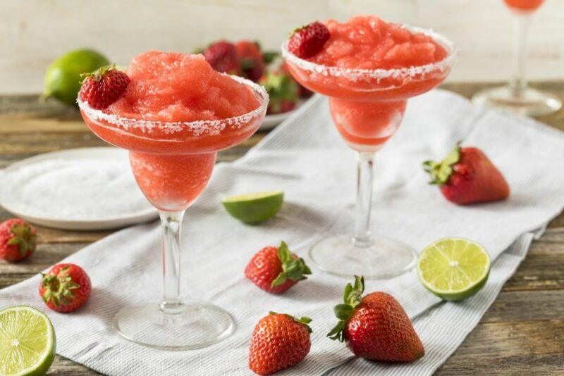 Two glasses of strawberry daiquiri with strawberries and limes