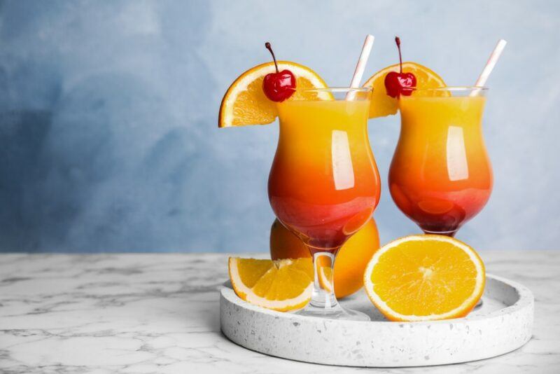 Two hurricane glasses filled with a tequila sunrise