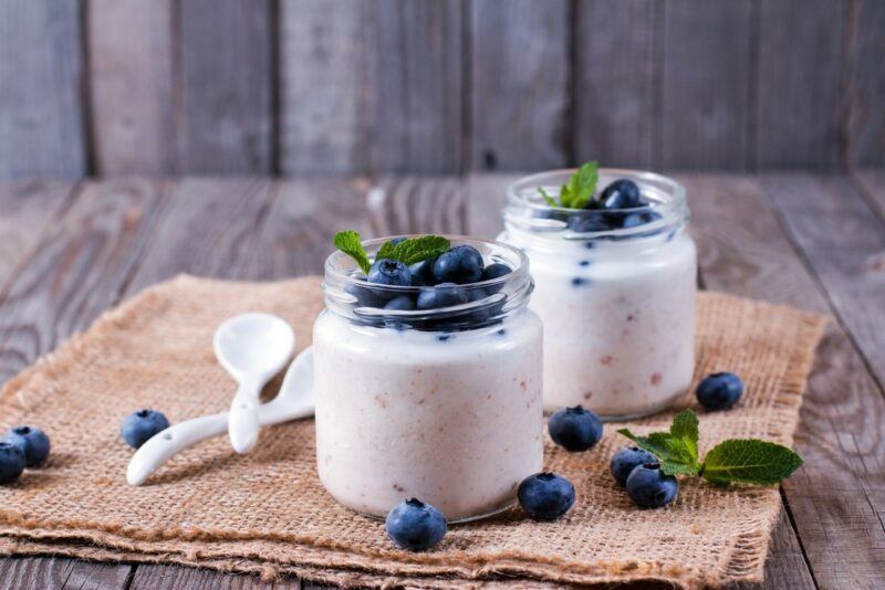 Two glasses of Activia yogurt with blueberries, next to spoons