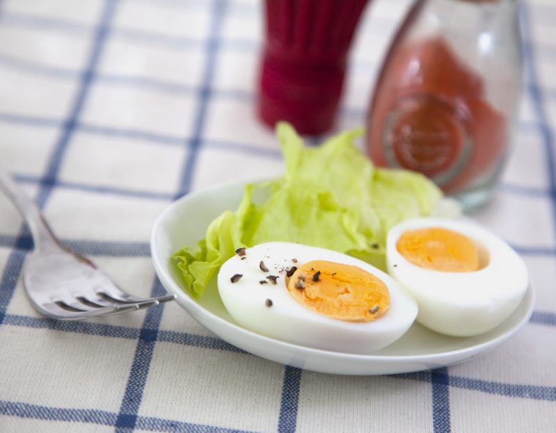 Hard boiled egg sliced in half, served on a small white plate