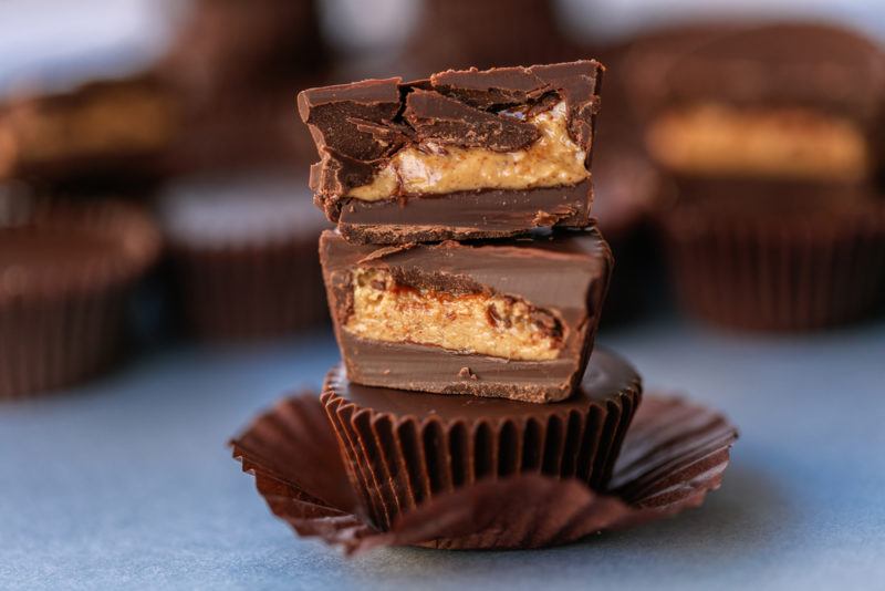 Two homemade peanut butter cups, one that has been cut in half, stacked on top of each other