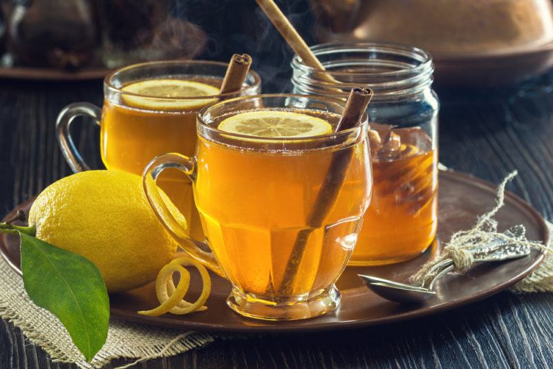 Two hot toddies in glasses on a tray with lemon and honey