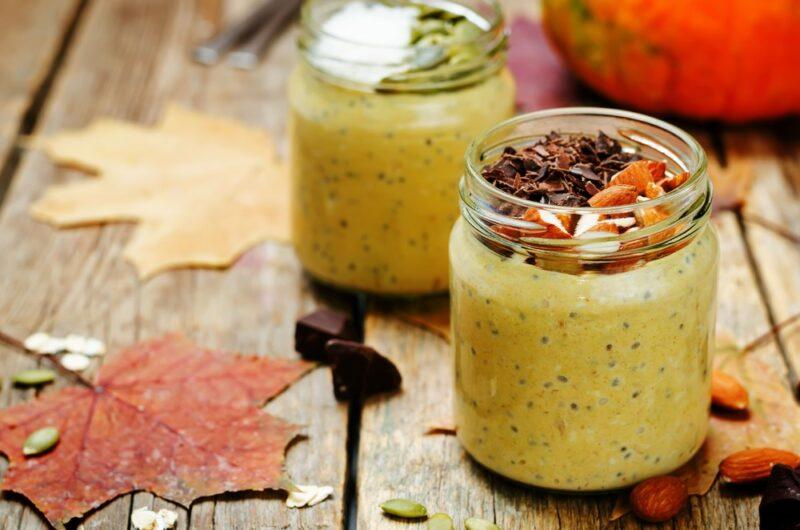 Two jars containing overnight oats and chia seeds on a table, with some maple leaves next to them