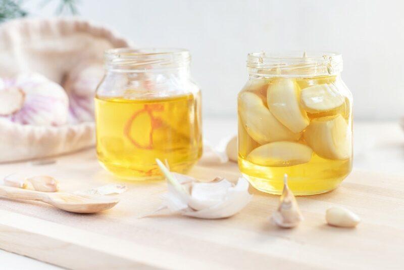 Two small jars. One contains honey and the other contains bulbs of garlic instead.