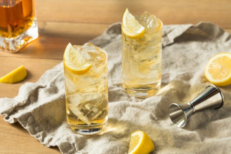 Two keto whiskey highball cocktails with lemon and a whiskey decanter in the background