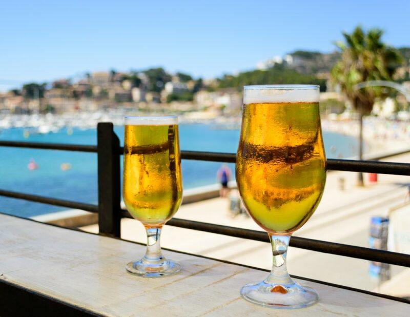 A deck with two fresh glasses of beer overlooking the ocean