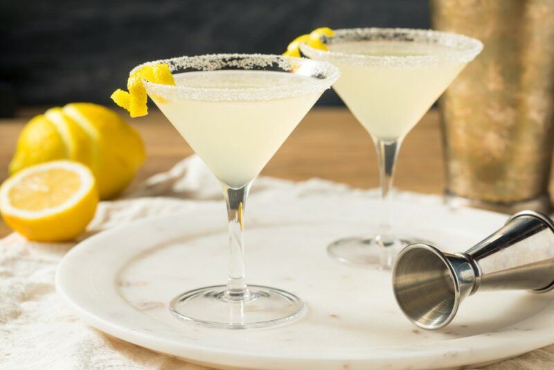 Two glasses containing a lemon drop cocktail with a lemon next to it