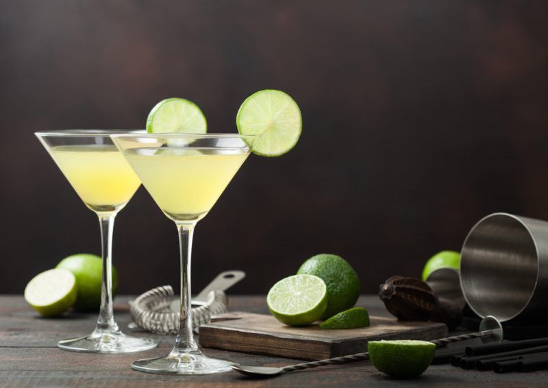 Two lime cocktails in martini glasses garnished with a slice of lime