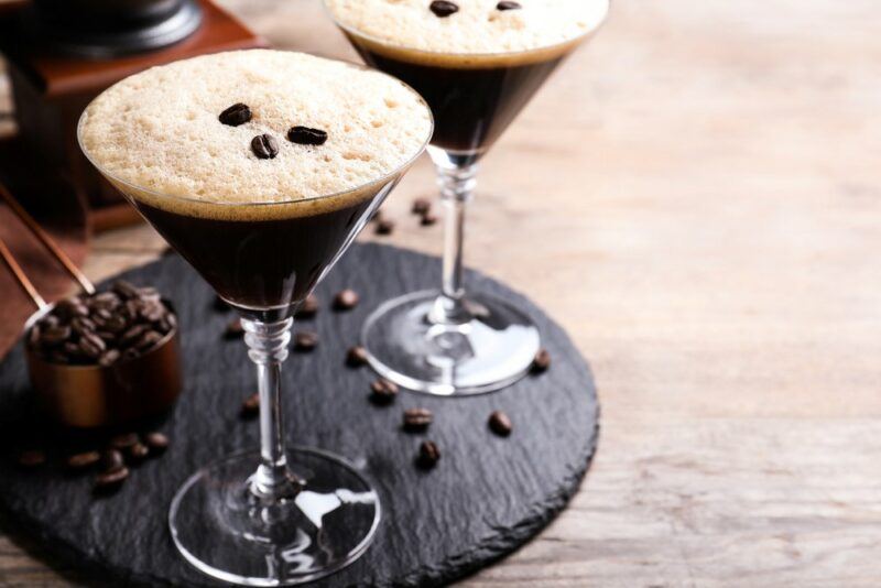 A black tray with two black velvet martinis, with coffee beans as a garnish