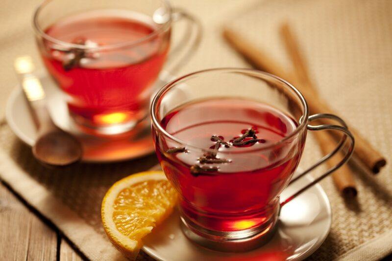 Two glass mugs with a spiced rum hot toddy, next to cinnamon sticks