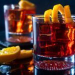 Two negroni cocktails in glasses with ice and a lemon twist