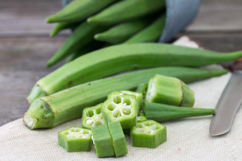 Two okra in the foreground, with more in the background, along with some small pieces