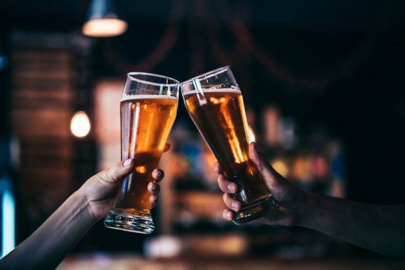 Two people clinking glasses of beer together