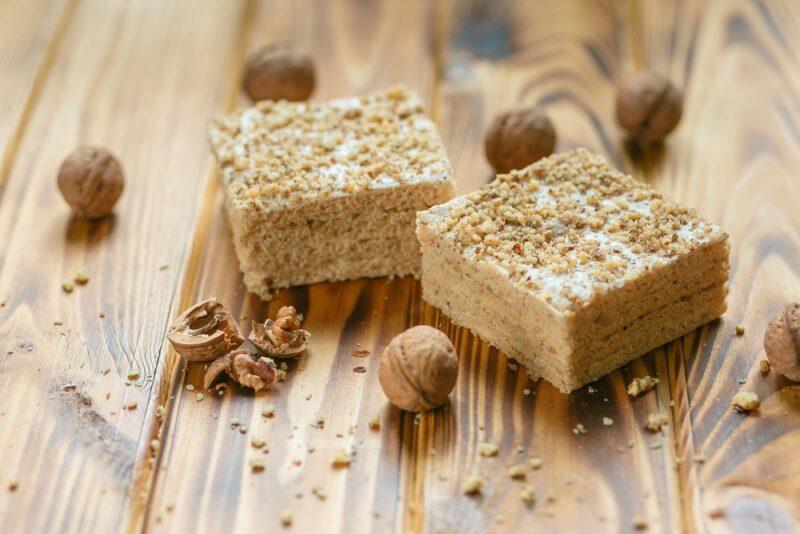 A wooden table with two pieces of a compressed pastila dessert, with some nuts on the table as well