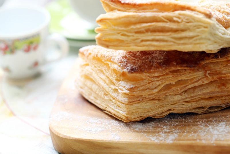 Two pieces of puff pastry with sugar on a wooden board