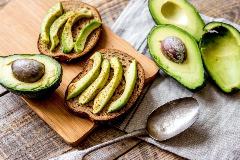 Slices of avocado on wholegrain toast, with a few avocado halves