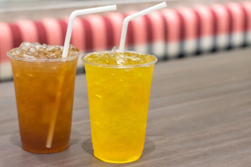 Two plastic cups filled with different types of loaded tea, one yellow and one the color of tea instead