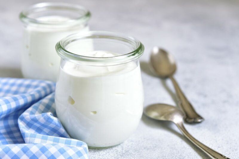 Two glass jars containing yogurt, next to spoons