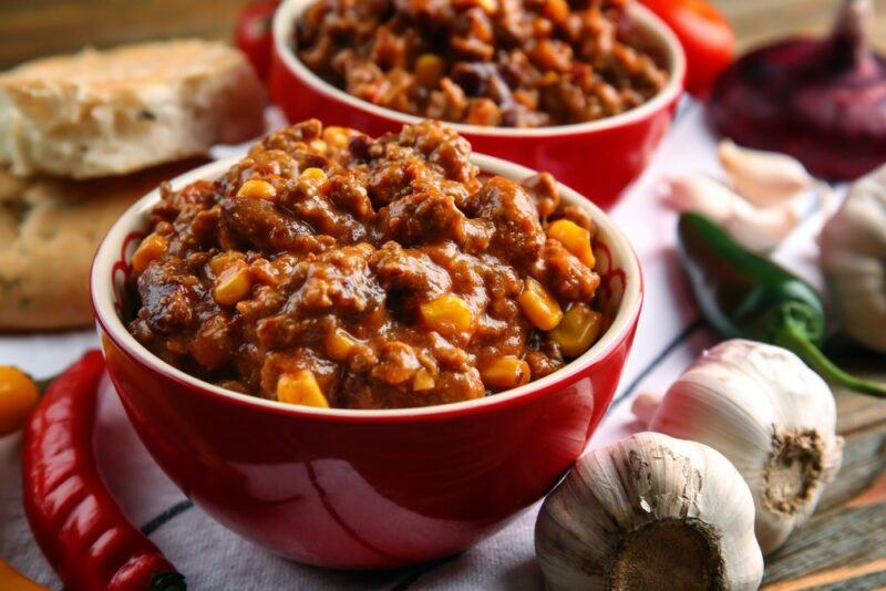 Two red bowls filled with chili to be served at a picnic