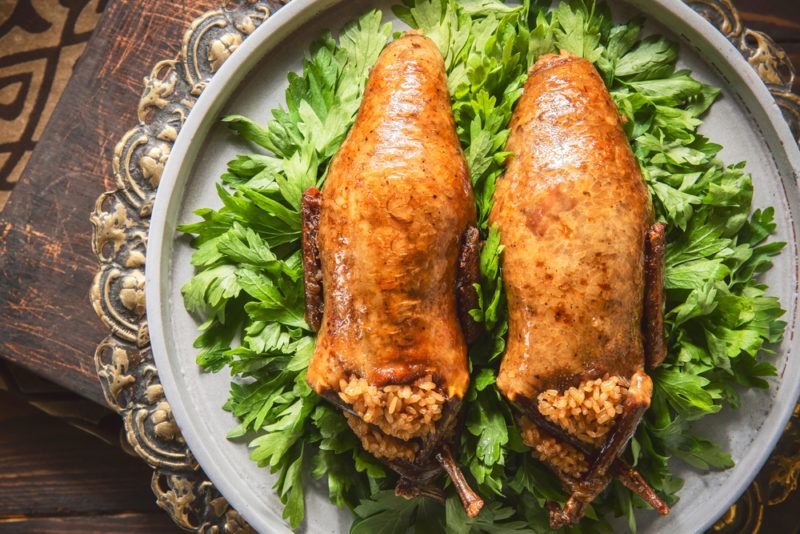 A plate with lettuce and two cooked and stuffed pigeons