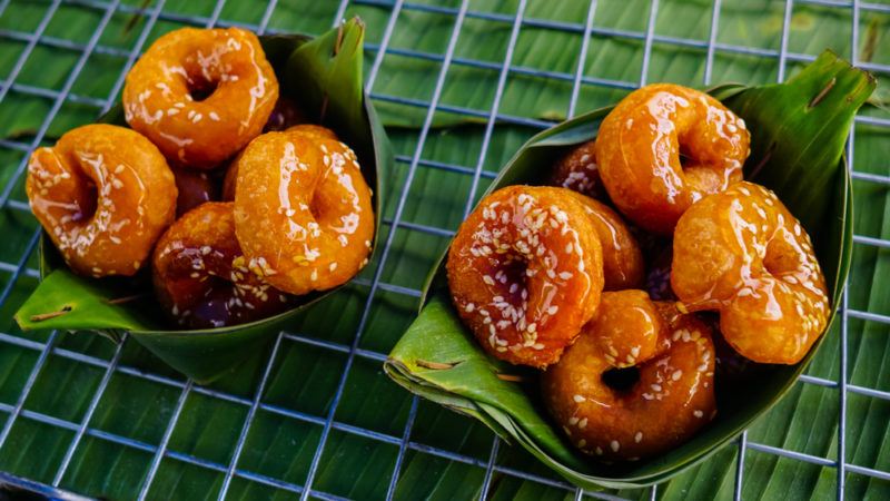 Two bamboo leaf baskets that contain Thai donuts