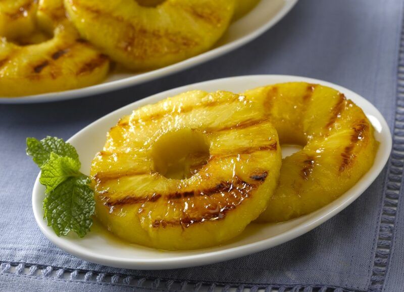 Two white plates with slices of grilled pineapple on a table