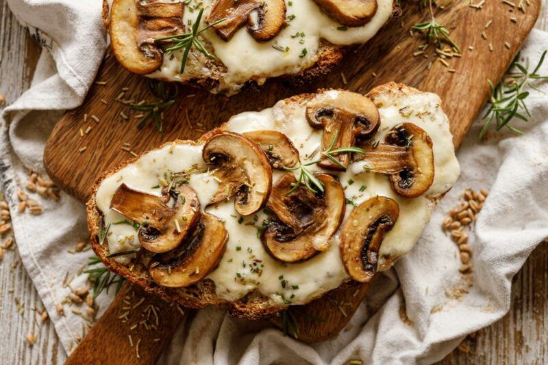 Two slices of sourdough, each with melted cheese and sliced mushrooms