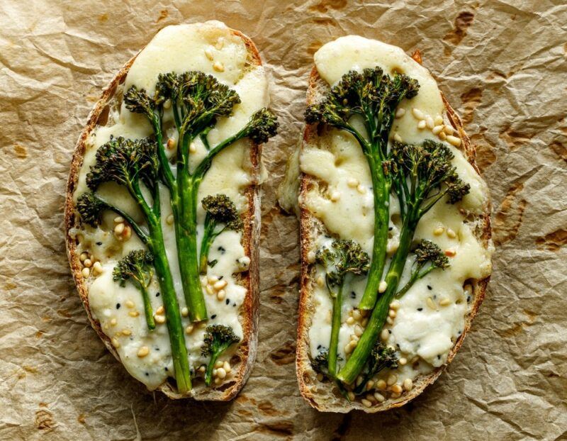 Two slices of sourdough with melted cheese and stalks of roast broccolini