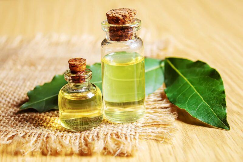 A light wooden table with bay leaves and two small bottles of olive oil