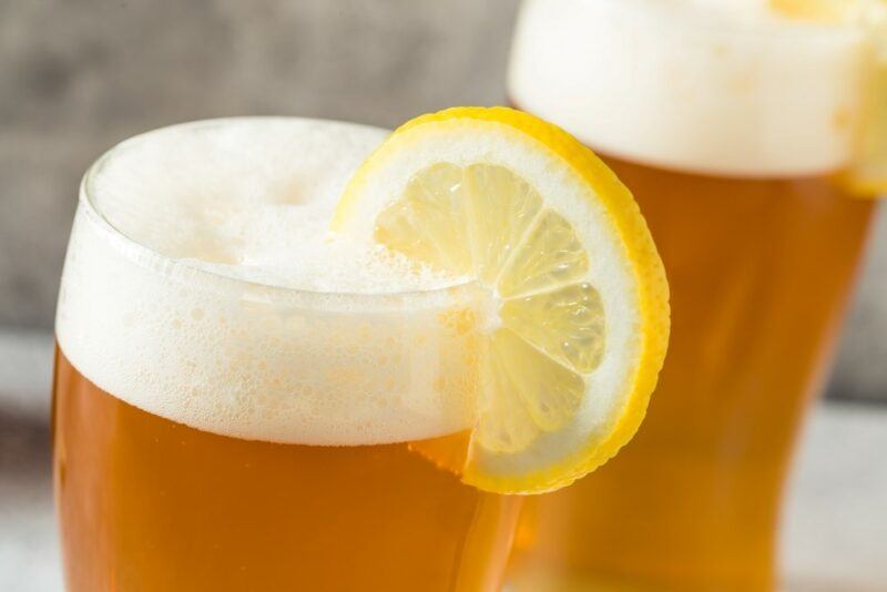 Two large glasses of summer ale with frothy heads and a slice of lemon each