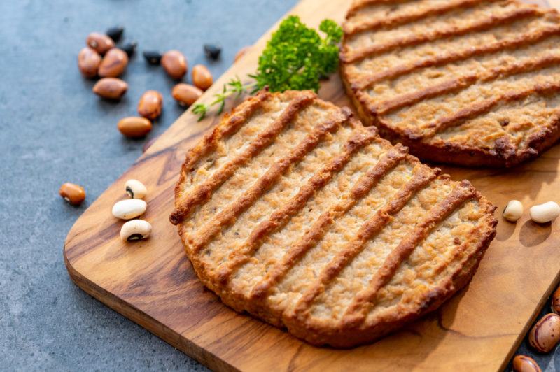 Two vegan meat patties on a wooden board