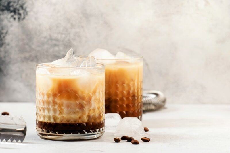 Two glasses containing white Russian cocktails against a light background