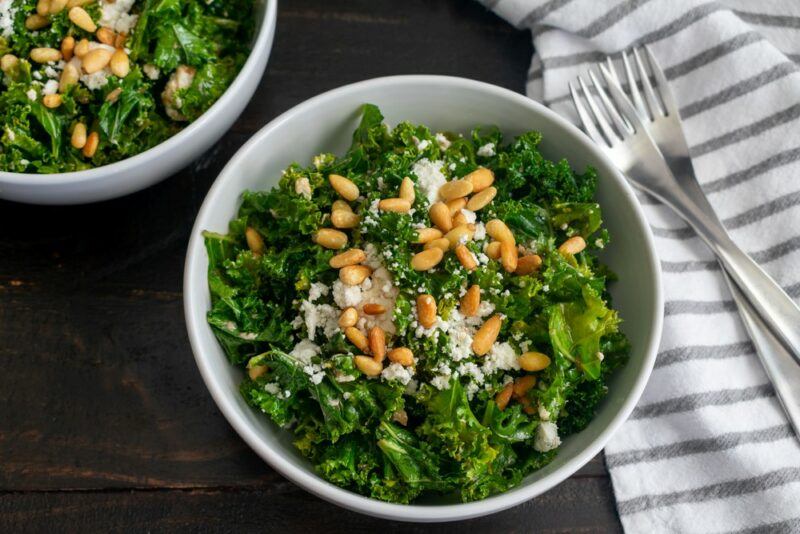 A leafy green salad that has been garnished with pine nuts and parmesan